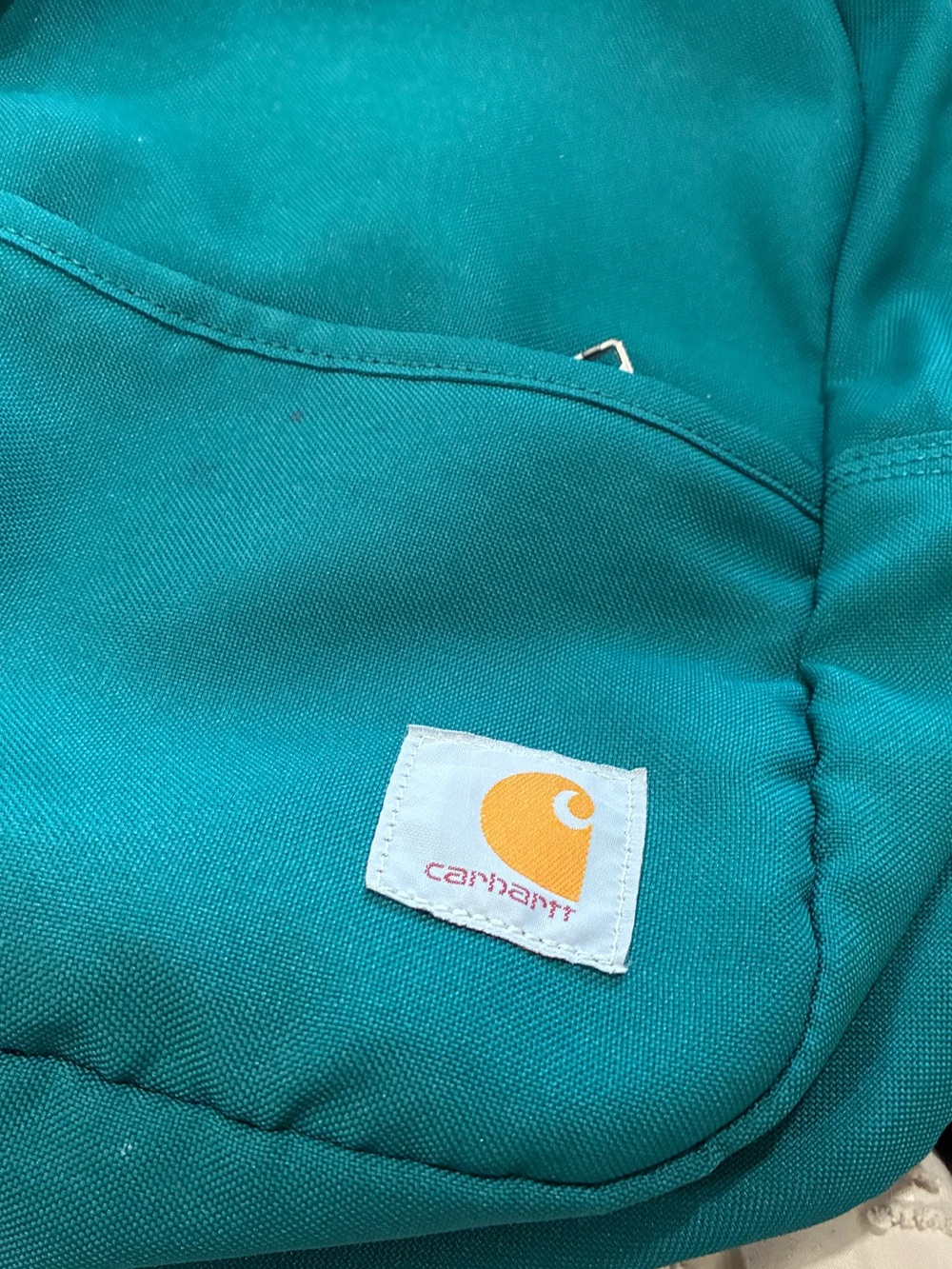Carhartt teal Mini Backpack front zippered pocket. - Picture 2 of 6